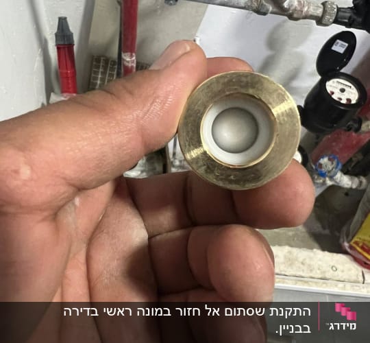 יד מחזיקה חלק מתכת ליד צינור מים
